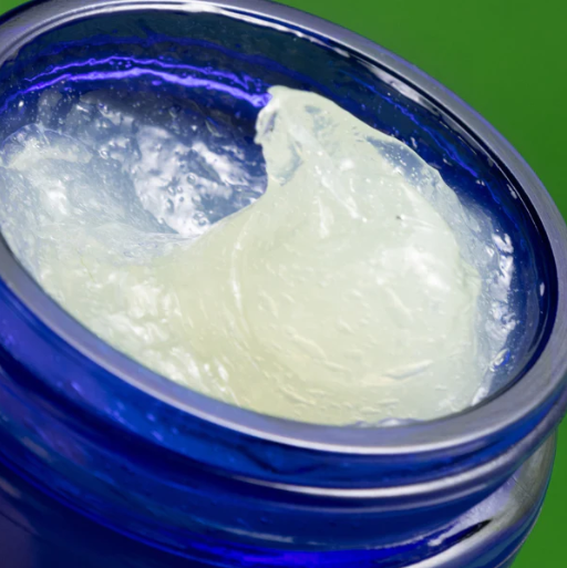 Close-up of a blue container with a white cream inside on a green background